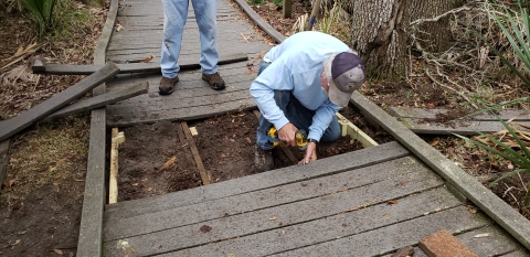 A refuge volunteer helps repair a boardwalk