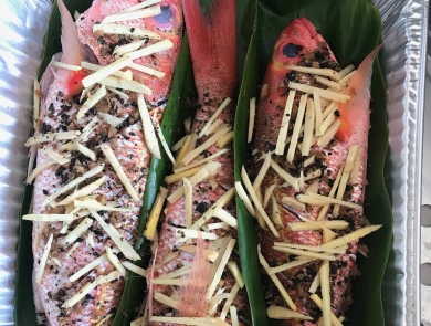 Three red fish in leaves are seasoned for cooking