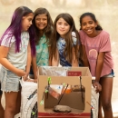 Four Nature Niños students stand for a photo with the arrows they shot during archery practice.
