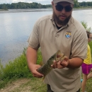 Image of FWS biologist holding a fish next to water.