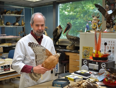 a man standing in a room holding a stuffed bird