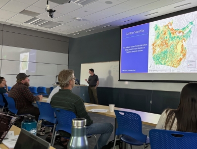 presentor in classroom of students with map on screen