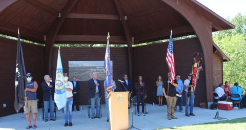 A dozen people stand to honor the color guard.