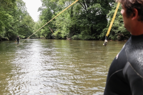 Two people standing in a river with a measuring tape stretched between them