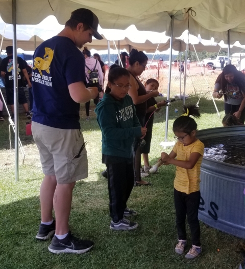 Children and adult standing around a large tank 