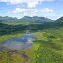 Clouds reflect in a wetland surrounded by mountains.