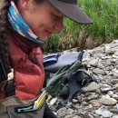 Woman wearing layered overalls, coat, neck gaitor and hat sets rat trip.