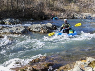 a man kayaks down a river in rapids