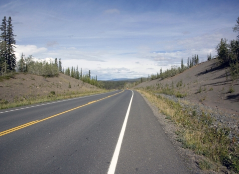 View of a two-lane highway cutting through Alaskan wilderness.