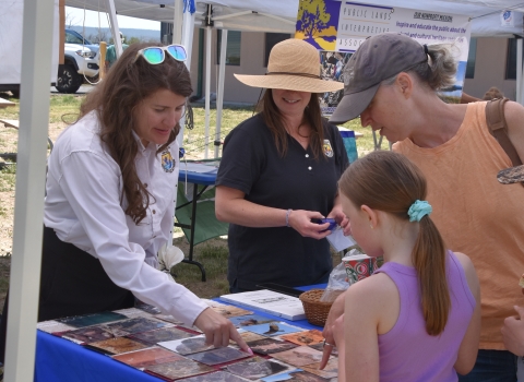 Two adults in FWS uniform show photographs to visitors.