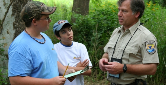 A man in a US Fish & Wildlife Service uniform talking to children in a forest