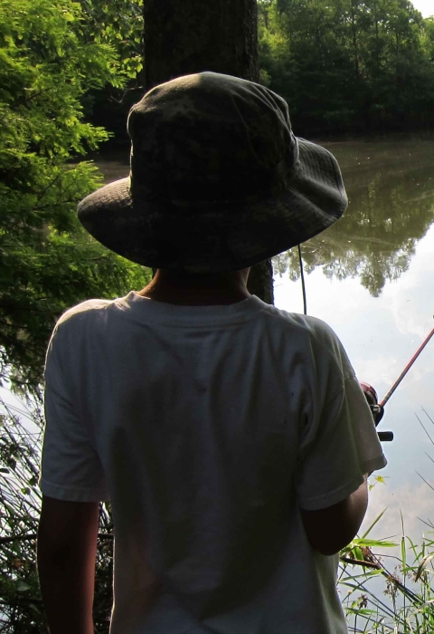 Boy with fishing pole at pond