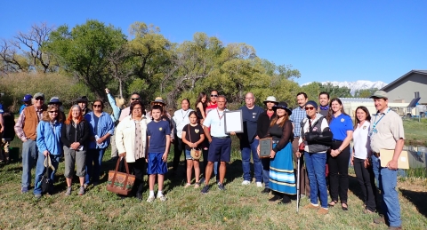 A group of people stand for a group photo outside.