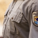 A close up of a U.S. Fish and Wildlife Service staff wearing the Service uniform's beige shirt with the shield patch on the shoulder.