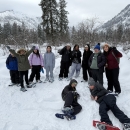 A group of 11 students gathered in snowshoes with mountains behind them