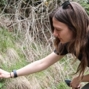 Woman kneeling down, reaching out toward a plant