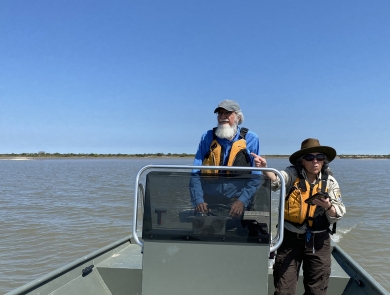 Two Service biologists stand in a boat near the coast of Texas.