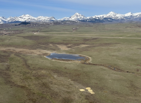aerial view of a landscape with mountains and grasslands and a lake