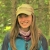 woman with dark hair smiles in front of green trees