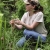 Female biologist kneeling among pitcher plants, holding swamp pink