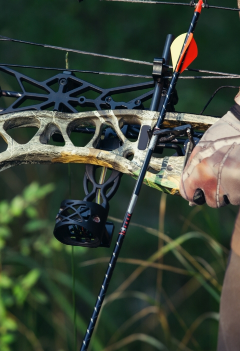 Arm of hunter in camo holding a bow.