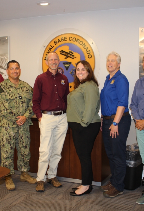 group of men and women pose for photo in conference room