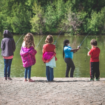 woman in a mask teaching youth how to fish