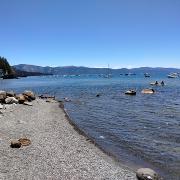 Shoreline of Lake Tahoe with boats in the distance.