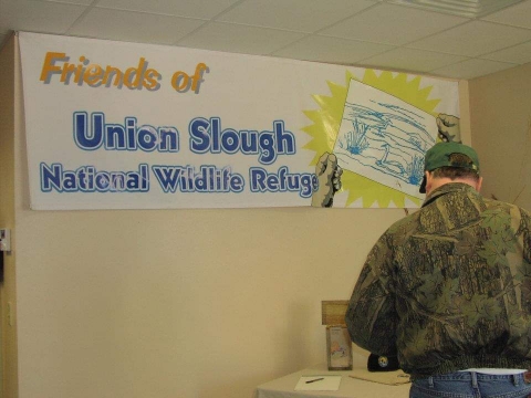 person standing in front of friends of union slough banner 