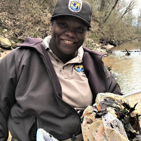 Angela stands in front of a creek holding a net