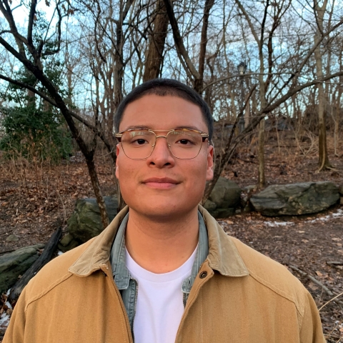 David Portilla stands in front of a small wooded area