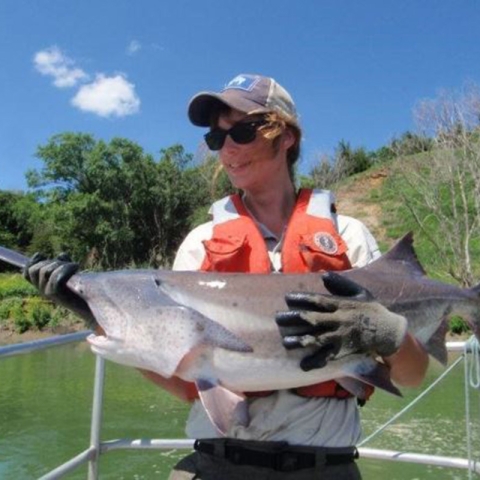 Maegan Spindler in her Service uniform holding a paddlefish in a boat. Image from In Memory of Robert Allan Klumb Facebook page, https://www.facebook.com/RobertAllanKlumb/photos/a.527813793939504/545656032155280/. 