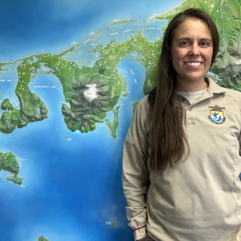 Woman with long hair in a FWS uniform standing in front of a wall map