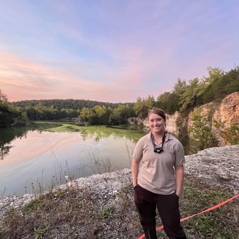 Kris Budd, a U.S. Fish and Wildlife Biologist, stands above a bluff overlooking a pond