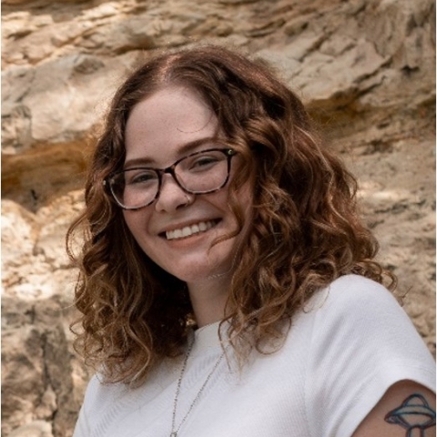 Alex smiles in glasses and white t-shirt