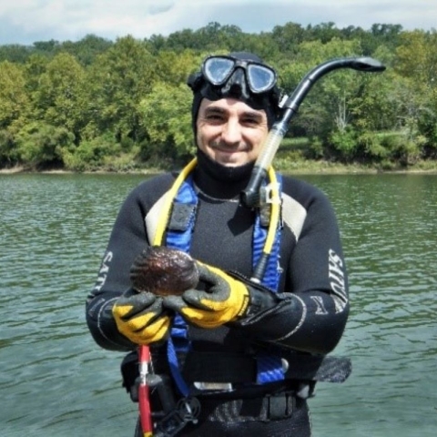 Photo of Andy Roberts in a wetsuit and dive gear holding a freshwater mussel by USFWS.