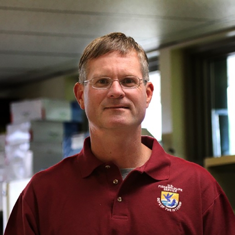 man in a lab with a fws logo on his shirt