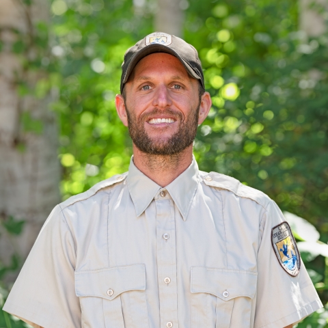 Service staff member in uniform with trees in the background