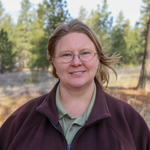 Portrait of a woman in a tan shirt and brown jacket