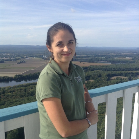 a woman with brown hair stands at a scenic overlook