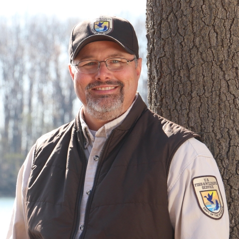 Man with ball cap and vest standing for photo