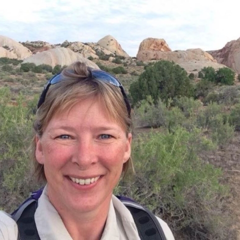 a selfie of a white woman with short, light brown hair in a desert