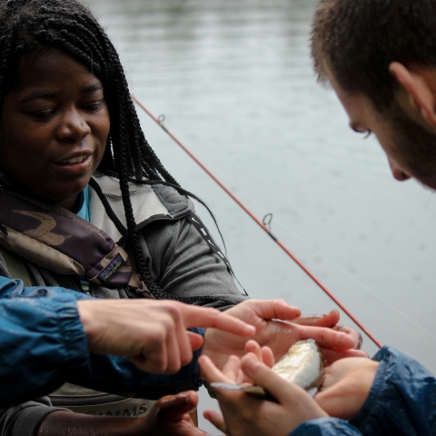 a woman holding a fish for a young man