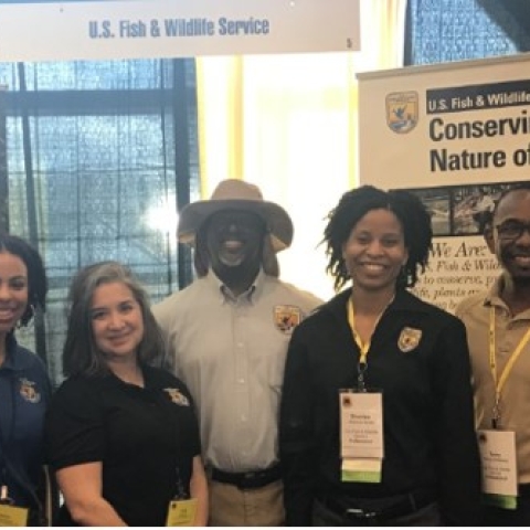 Jerome wears a hat and smiles among FWS staff members 