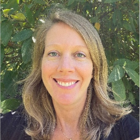 Kate smiles in front of green leaves