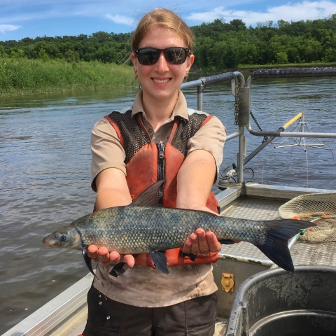 Woman on boat holding fish and smiling