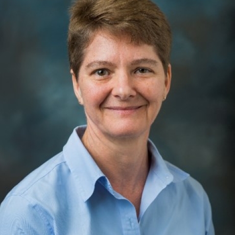 Laura smiles in a light blue button down shirt