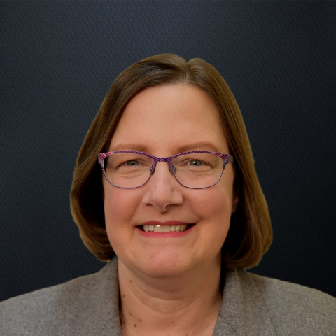 A head shot of a white woman with brown hair and glasses