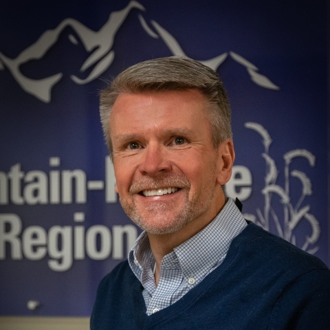 Matt Hogan stands in front of a banner that says Mountain-Prairie region