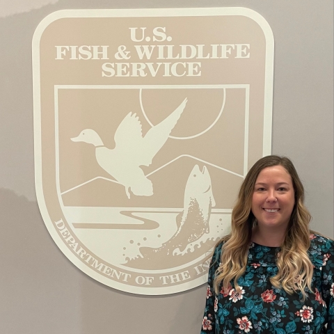 a woman stands and smiles next to a large Service logo